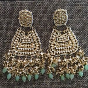 Earrings made with Kundun, pearls, and has aqua colored stones on the bottom.
